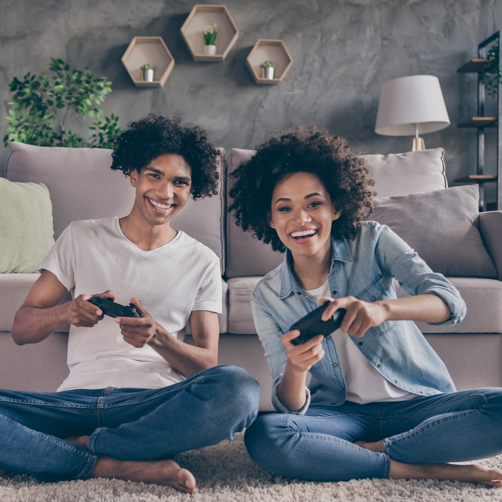 Paar beim Spielen an den Konsolen vor dem Sofa