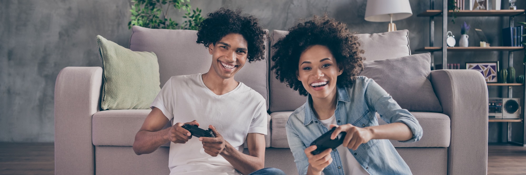 Pärchen spielt Computerspiel mit Konsolen im Wohnzimmer 